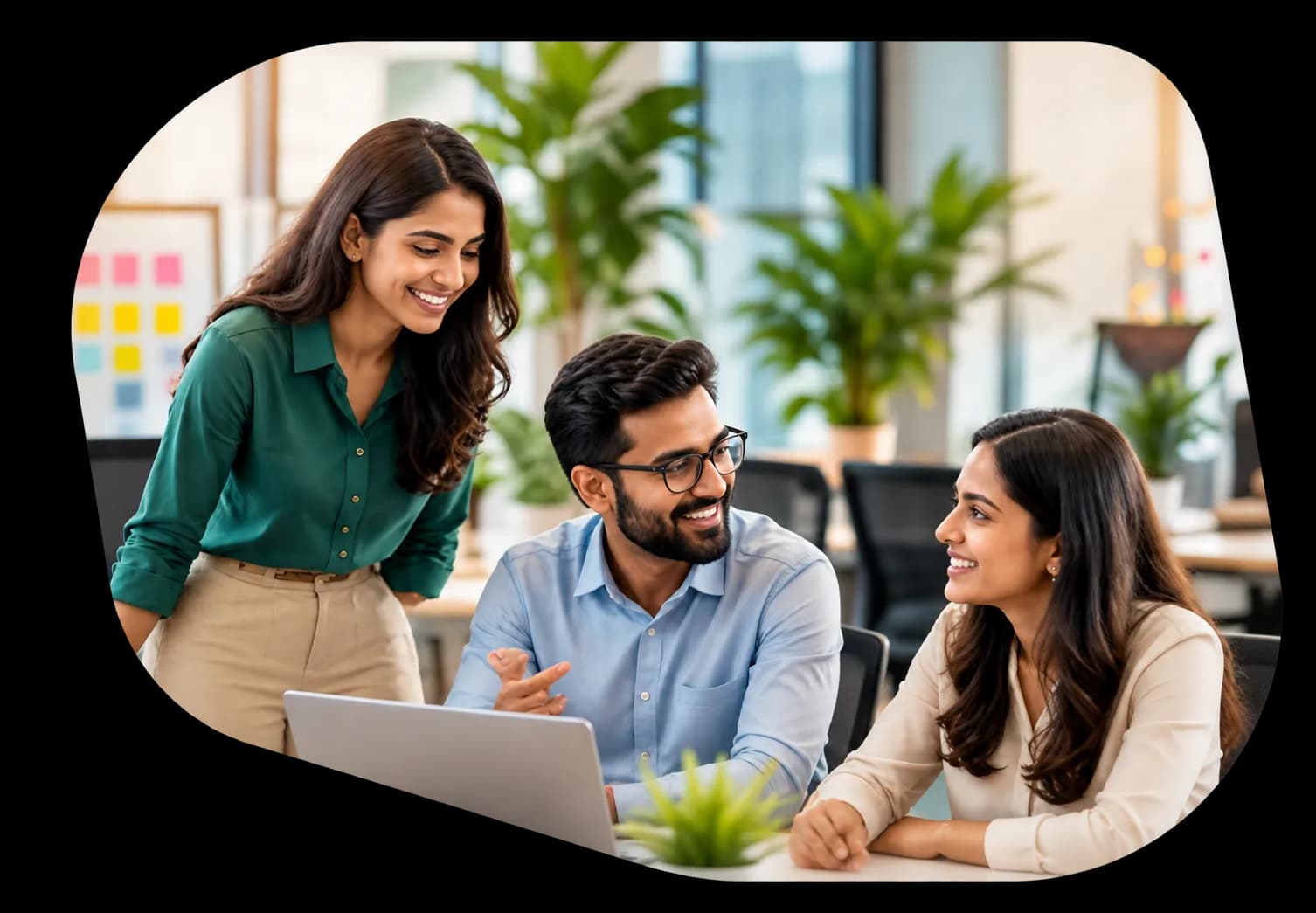 Colleagues smiling and collaborating around a laptop